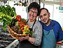 Ein Bild der beiden Restaurantinhaber mit einem Korb voller Gemüse.
